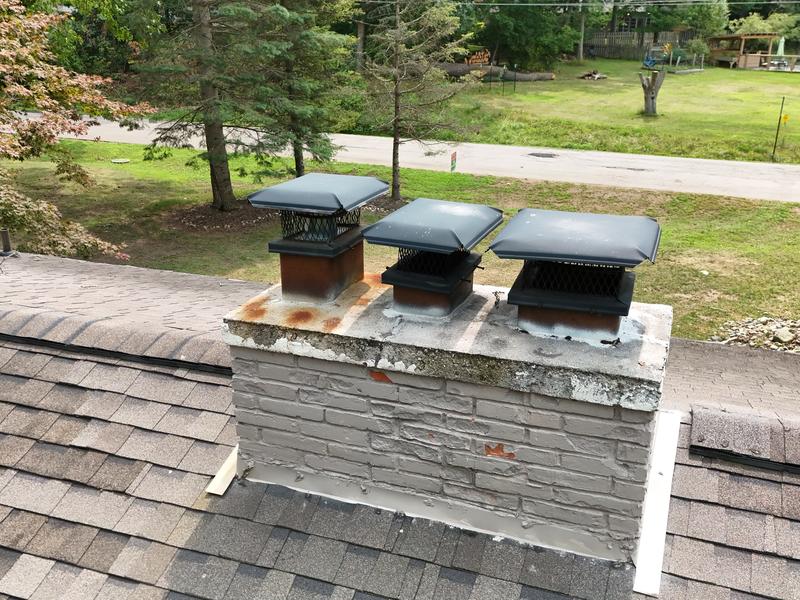A masonry chimney with three caps and fresh flashing